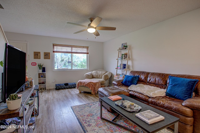 living room with a textured ceiling, light wood-type flooring, and ceiling fan