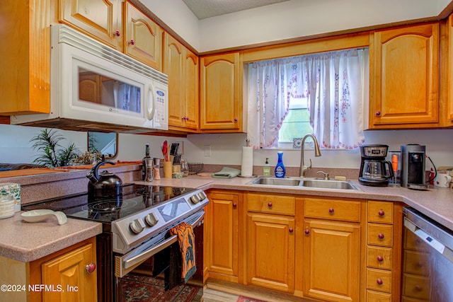 kitchen with a textured ceiling, appliances with stainless steel finishes, and sink