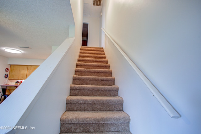 staircase with a textured ceiling