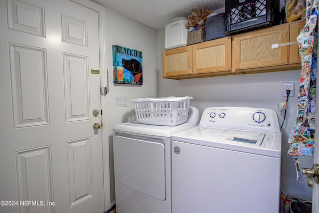 washroom with independent washer and dryer, a textured ceiling, and cabinets