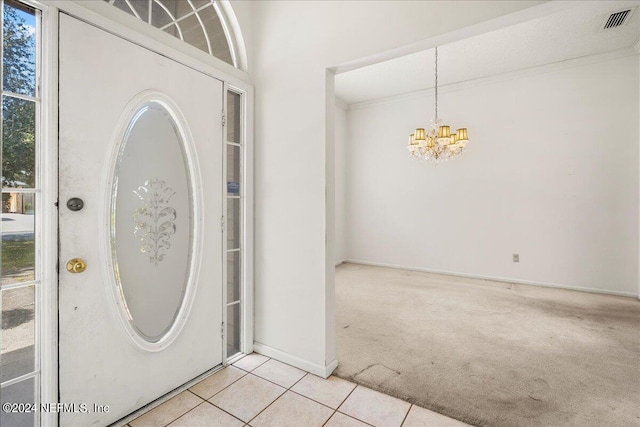 carpeted foyer entrance with a notable chandelier