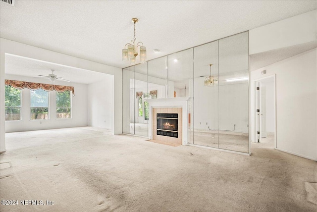 unfurnished living room featuring carpet floors, a textured ceiling, ceiling fan with notable chandelier, and a fireplace