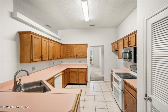 kitchen featuring kitchen peninsula, sink, light tile patterned floors, a textured ceiling, and white appliances