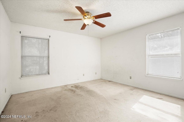 carpeted spare room with a textured ceiling and ceiling fan