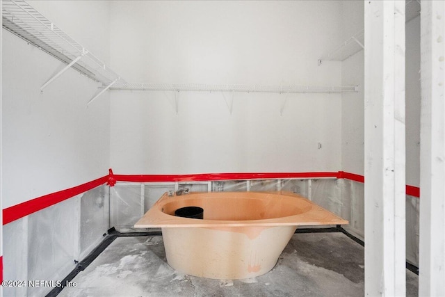 bathroom with a bathing tub and concrete floors