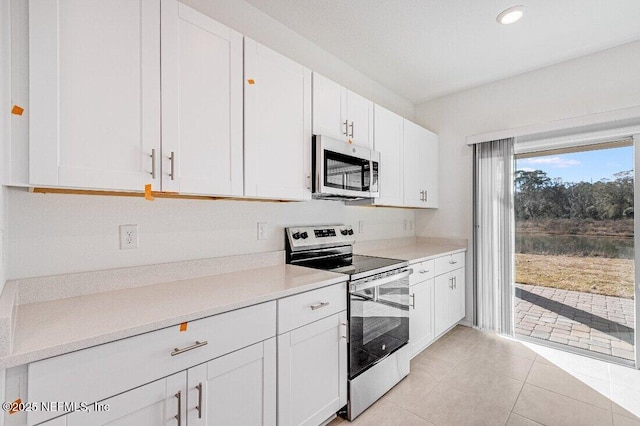 kitchen featuring stainless steel appliances, light tile patterned floors, and white cabinets