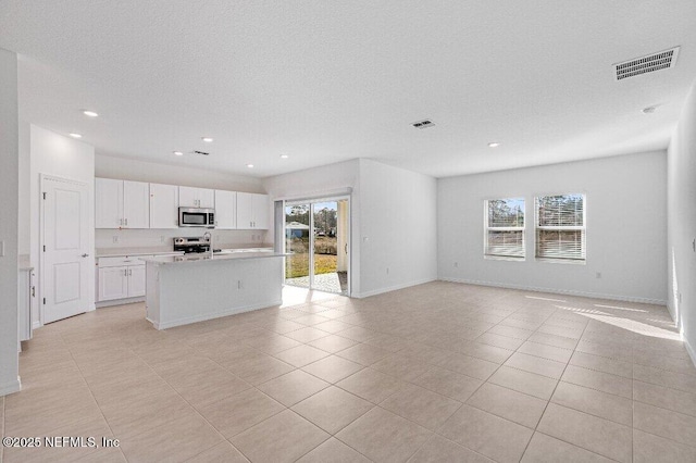 kitchen with white cabinetry, a kitchen island with sink, stainless steel appliances, and plenty of natural light