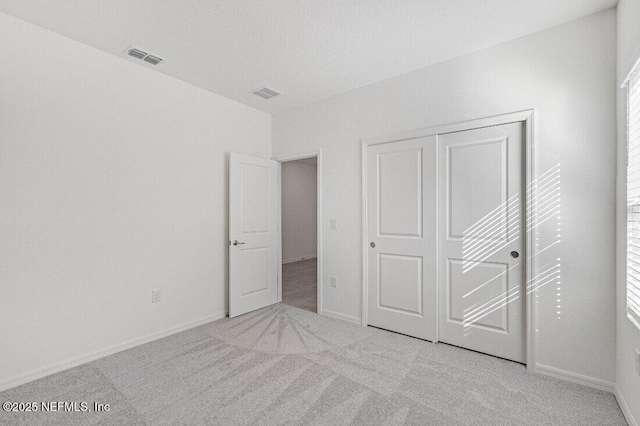 unfurnished bedroom featuring light colored carpet and a closet