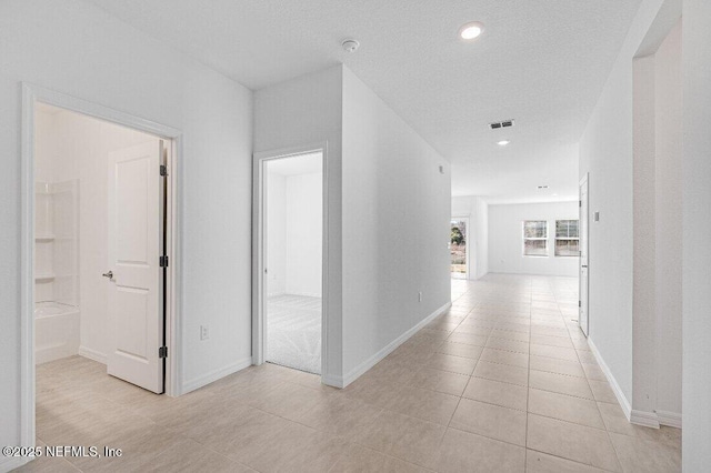 corridor featuring a textured ceiling and light tile patterned flooring