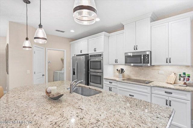 kitchen featuring pendant lighting, sink, separate washer and dryer, appliances with stainless steel finishes, and white cabinetry