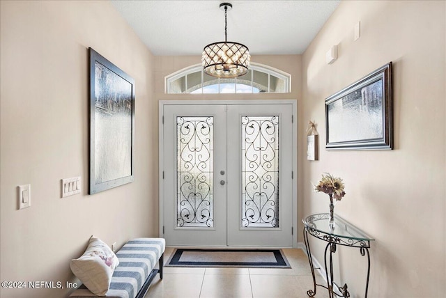 tiled entrance foyer with a chandelier, french doors, and a textured ceiling