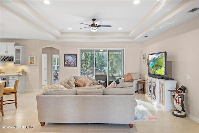 living room featuring a tray ceiling and ceiling fan