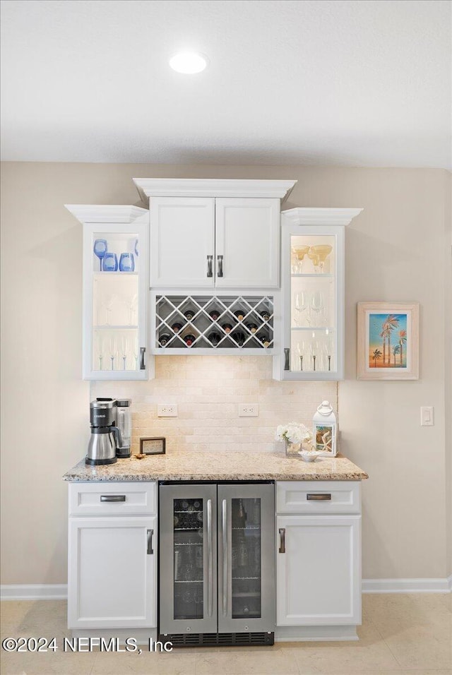 bar featuring white cabinets, light stone countertops, and beverage cooler