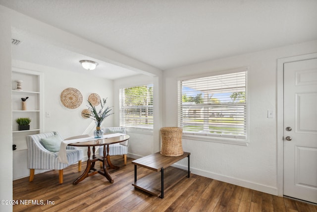 sitting room featuring built in shelves and dark wood-type flooring