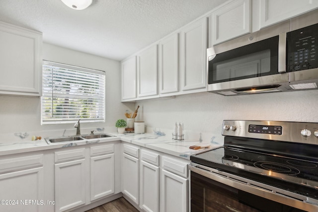 kitchen featuring hardwood / wood-style flooring, white cabinetry, sink, and appliances with stainless steel finishes