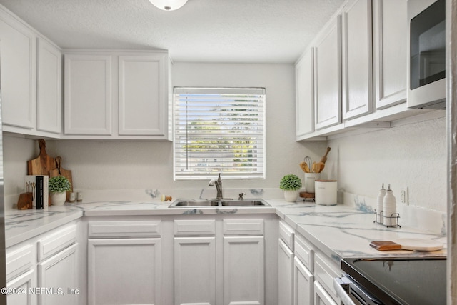 kitchen with a textured ceiling, sink, white cabinetry, and stainless steel appliances