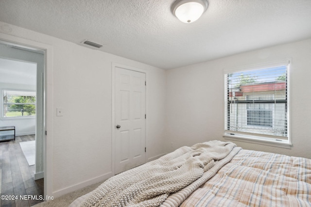 bedroom with hardwood / wood-style floors and a textured ceiling