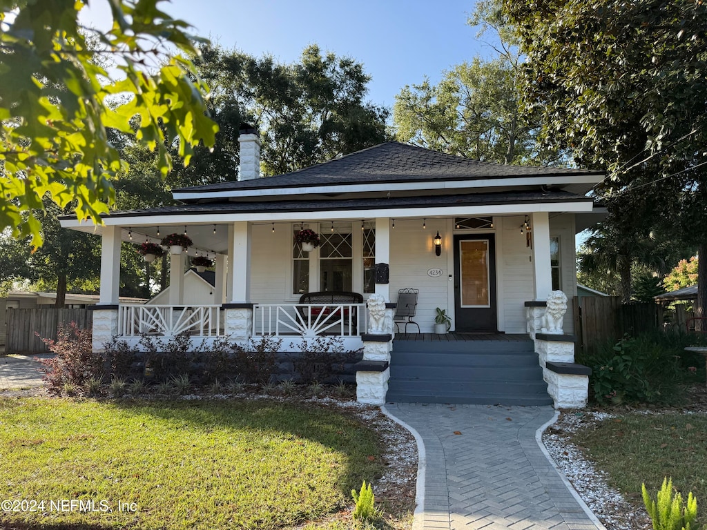 bungalow featuring covered porch and a front lawn