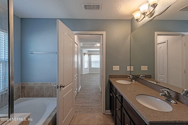 bathroom featuring a tub to relax in, a textured ceiling, and vanity