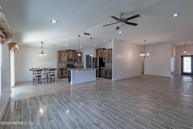 kitchen featuring tasteful backsplash, a center island, pendant lighting, stainless steel appliances, and ceiling fan with notable chandelier