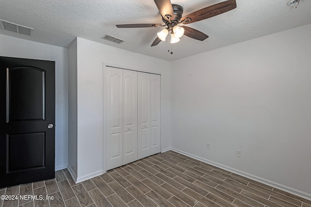 unfurnished bedroom with a textured ceiling, a closet, and ceiling fan