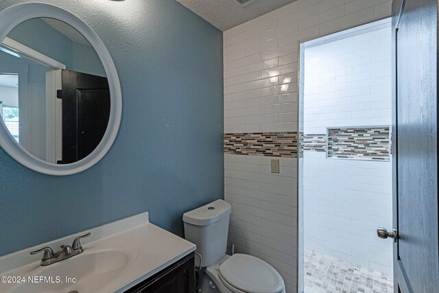 bathroom with vanity, tiled shower, and toilet