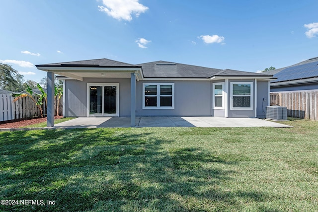 rear view of property featuring a patio, a yard, and central AC