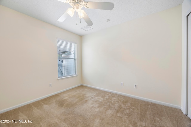 spare room featuring a textured ceiling, light colored carpet, and ceiling fan