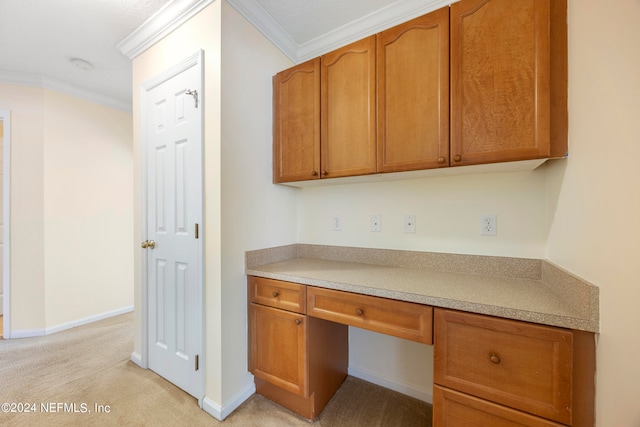 unfurnished office featuring built in desk, crown molding, and light carpet