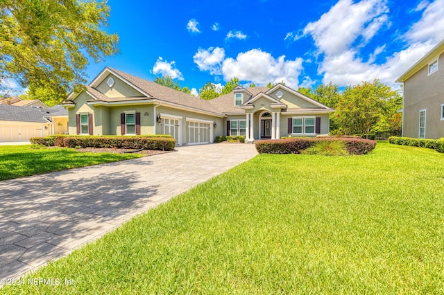 view of front facade with decorative driveway, an attached garage, stucco siding, and a front yard