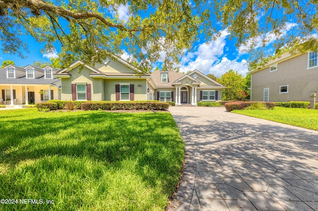 view of front facade featuring a front lawn, decorative driveway, and stucco siding