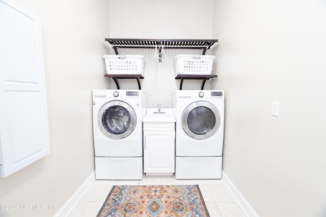 clothes washing area with light tile patterned flooring, cabinet space, washer and clothes dryer, and baseboards