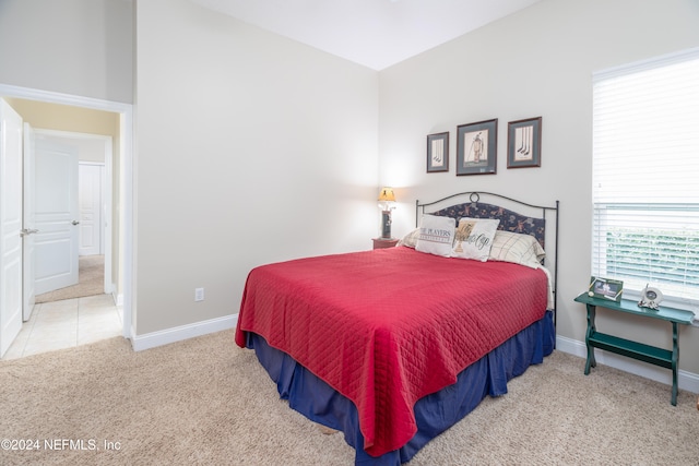 bedroom featuring light carpet, baseboards, and light tile patterned floors