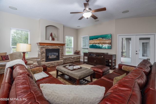 living room featuring ceiling fan, wood finished floors, a textured ceiling, french doors, and a fireplace