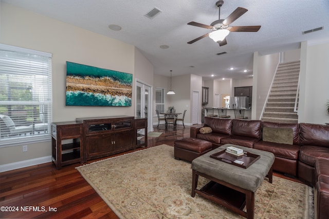 living area with stairway, dark wood finished floors, visible vents, and baseboards