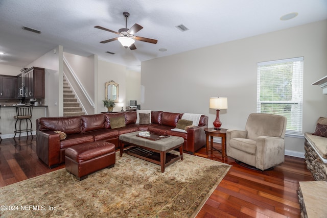 living room with dark wood-style flooring, visible vents, and stairs