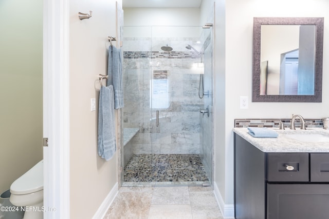 bathroom featuring a stall shower, vanity, toilet, and baseboards