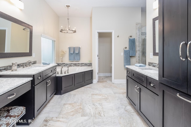 bathroom featuring two vanities, a sink, a garden tub, and an inviting chandelier