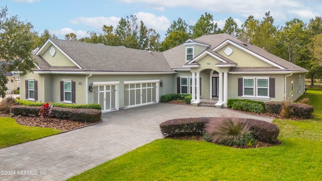 view of front of home featuring a front lawn, decorative driveway, an attached garage, and stucco siding