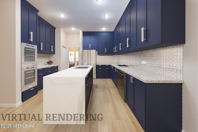 kitchen featuring a sink, blue cabinetry, light wood-type flooring, backsplash, and an island with sink