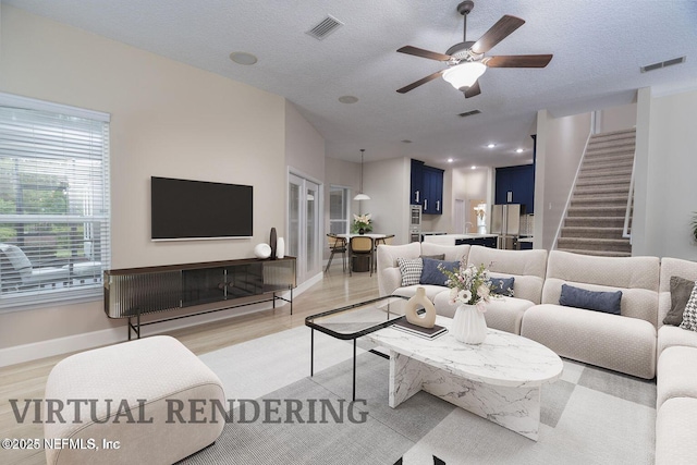 living area featuring a textured ceiling, light wood-type flooring, and visible vents