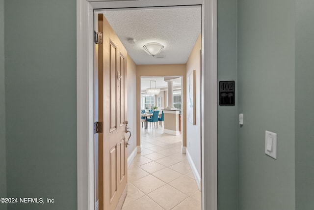 corridor featuring a textured ceiling and light tile patterned floors