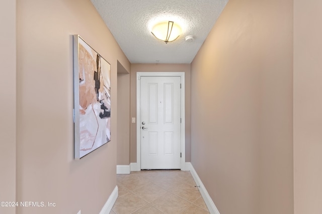 doorway to outside featuring a textured ceiling and light tile patterned floors