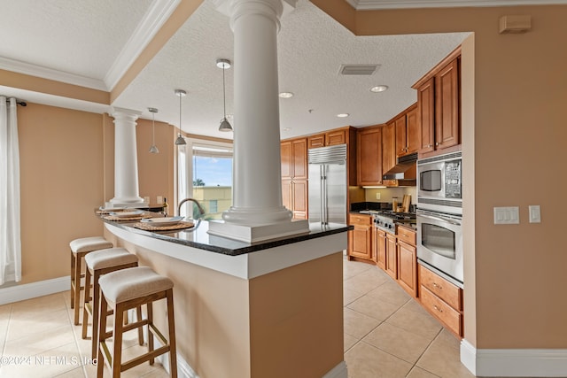 kitchen with light tile patterned flooring, a textured ceiling, decorative light fixtures, built in appliances, and crown molding