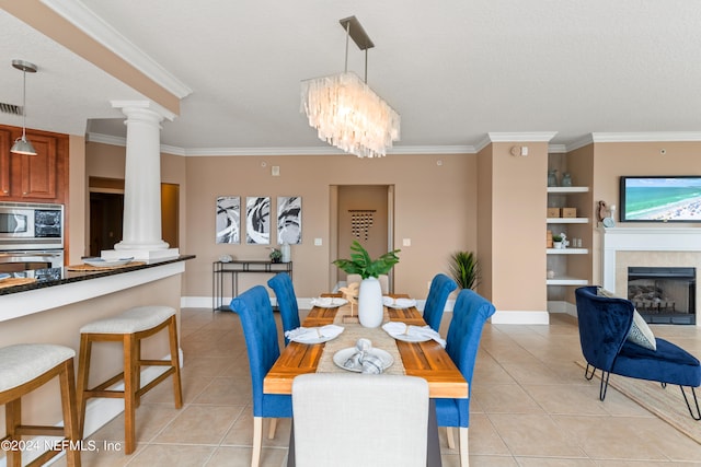 tiled dining area with a fireplace, a textured ceiling, ornate columns, ornamental molding, and an inviting chandelier