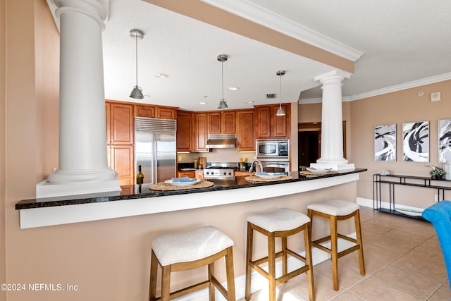 kitchen featuring kitchen peninsula, a breakfast bar, built in appliances, pendant lighting, and crown molding