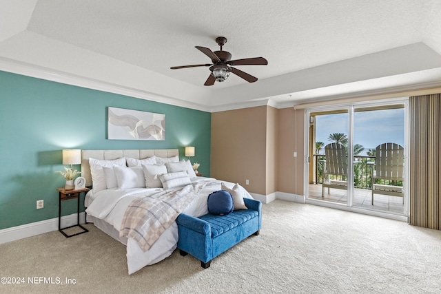 carpeted bedroom with ceiling fan, a raised ceiling, a textured ceiling, and access to exterior