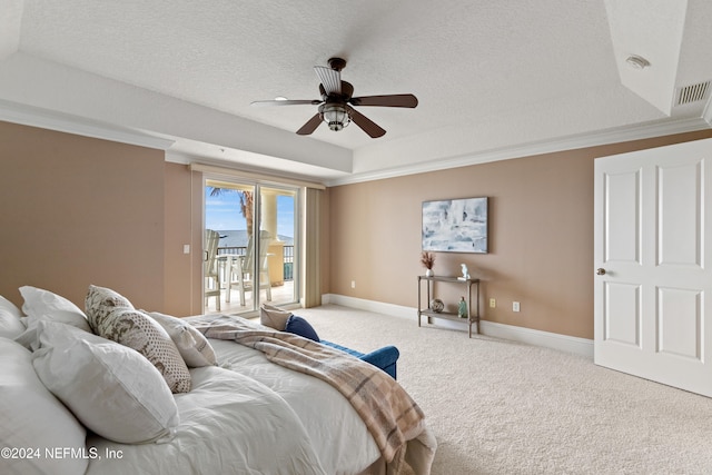 carpeted bedroom with a textured ceiling, a tray ceiling, access to exterior, ceiling fan, and crown molding