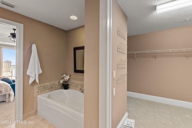 bathroom featuring a textured ceiling, a tub to relax in, and ceiling fan