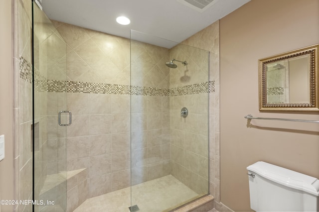 bathroom with a shower with shower door and toilet